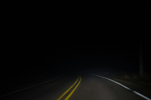 two-lane highway fading into complete night darkness