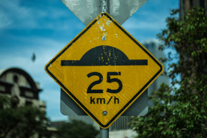 yellow and black speed bump road sign with 25 kilometers per hour written on it