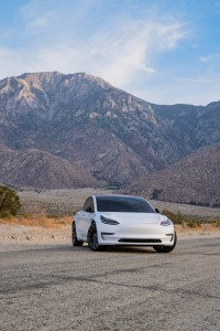 white electric vehicle parked on desert mountain road