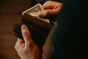 close up of hands taking one United States dollar out of a man's wallet