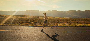 jogger running on a paved street through a desert mountain landscape