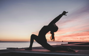 silhouette of a woman doing a yoga pose against a sunset backdrop
